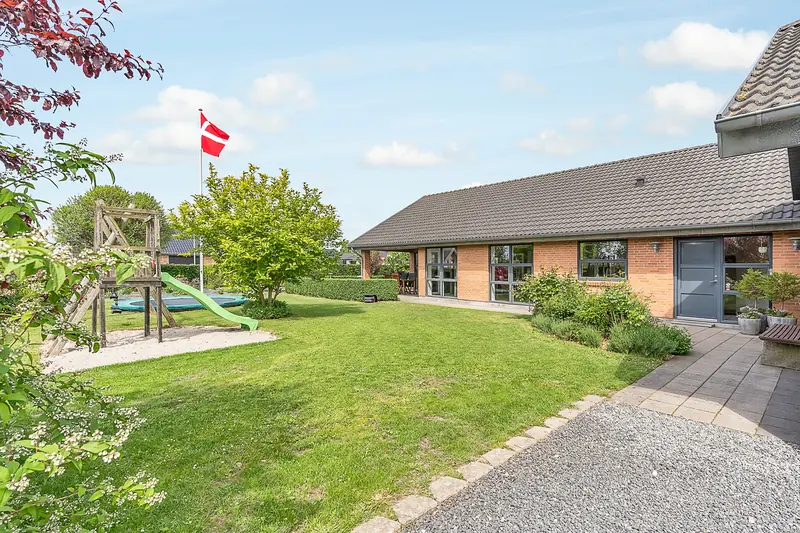 Huset set fra indkørslen med flagstang